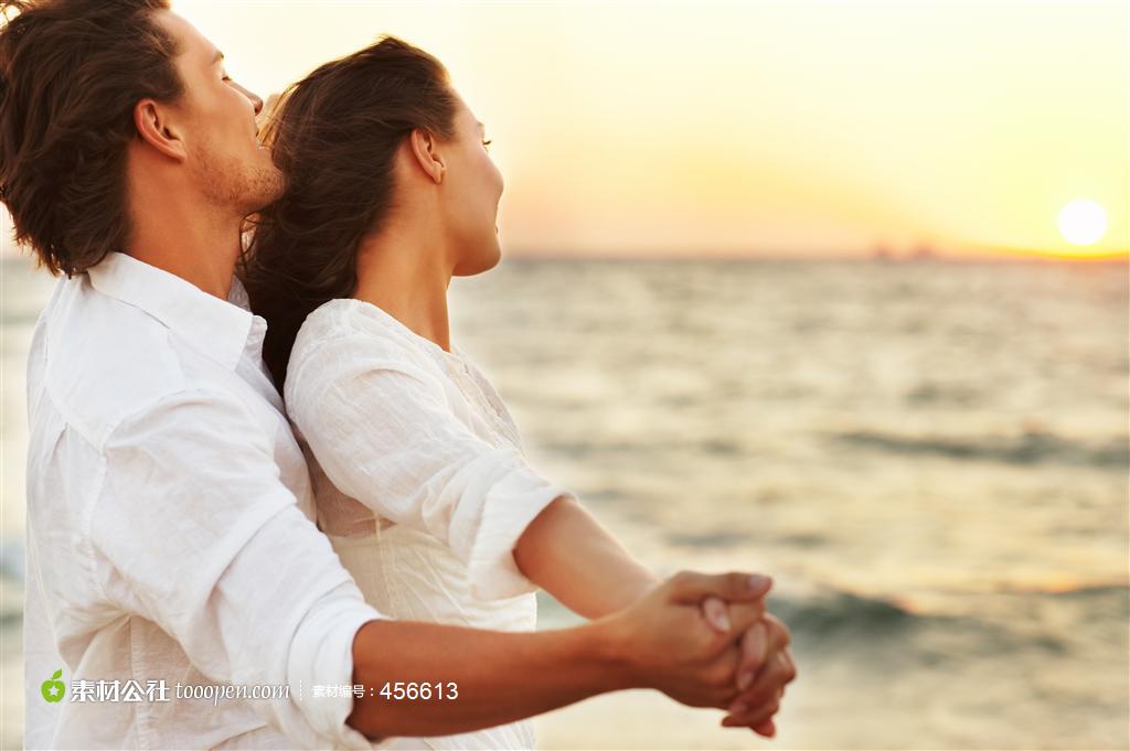欧美情侣张开双手拥抱看海边夕阳图片素材