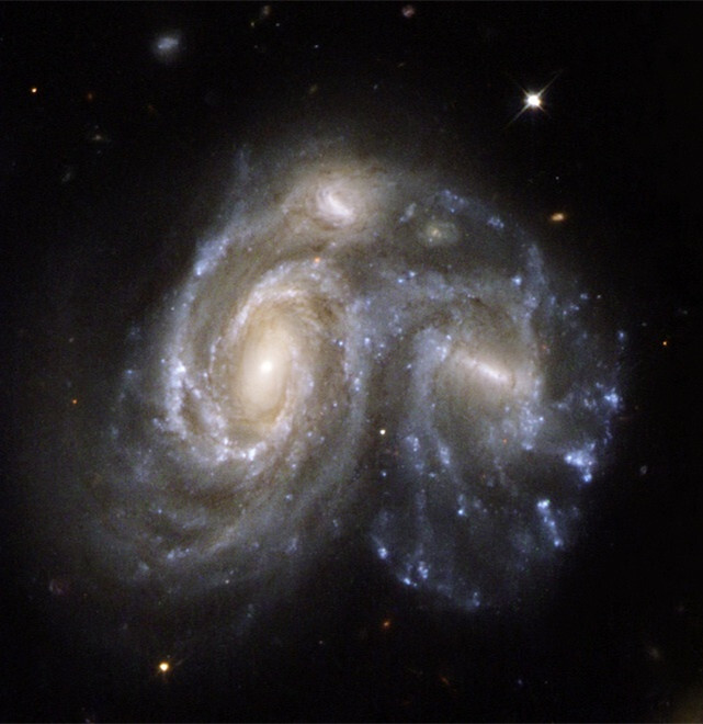 这两个漩涡星系正发生撞击,在两者交接的旋臂结构中有大量的新生恒星