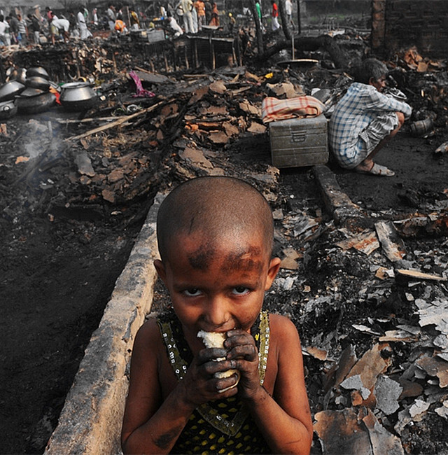 苦难中挣扎的孩子:印度santoshpur贫民窟,大火后一片狼藉.