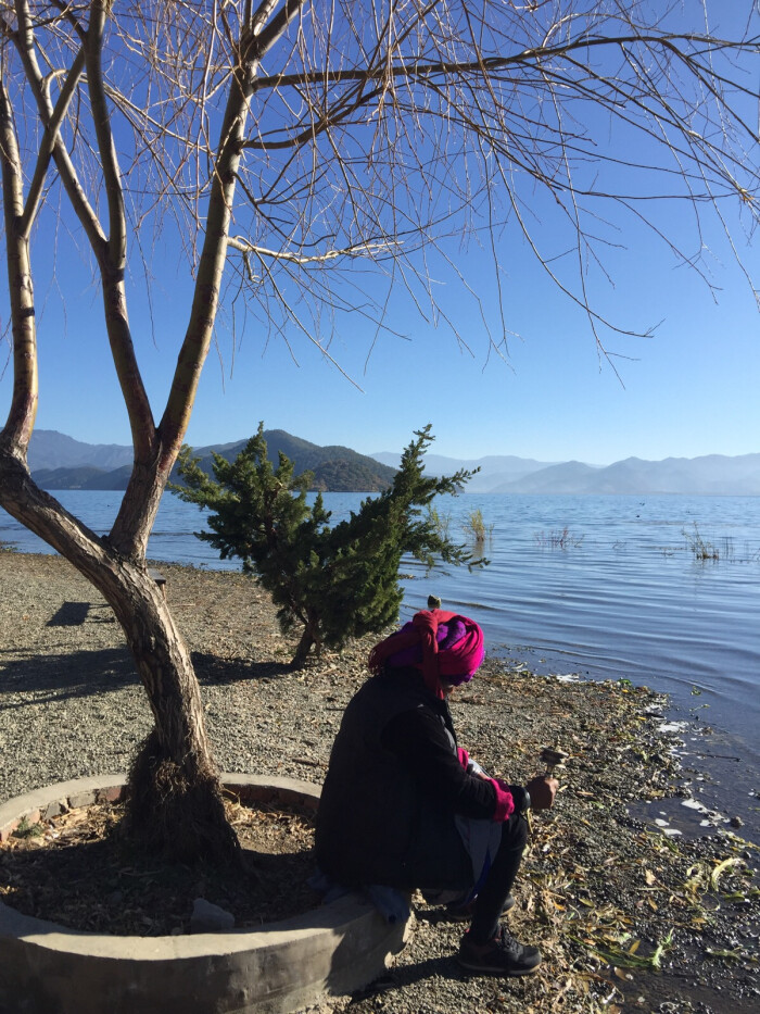 清晨的泸沽湖,一个人坐在湖边静静的转转经筒的阿嬷